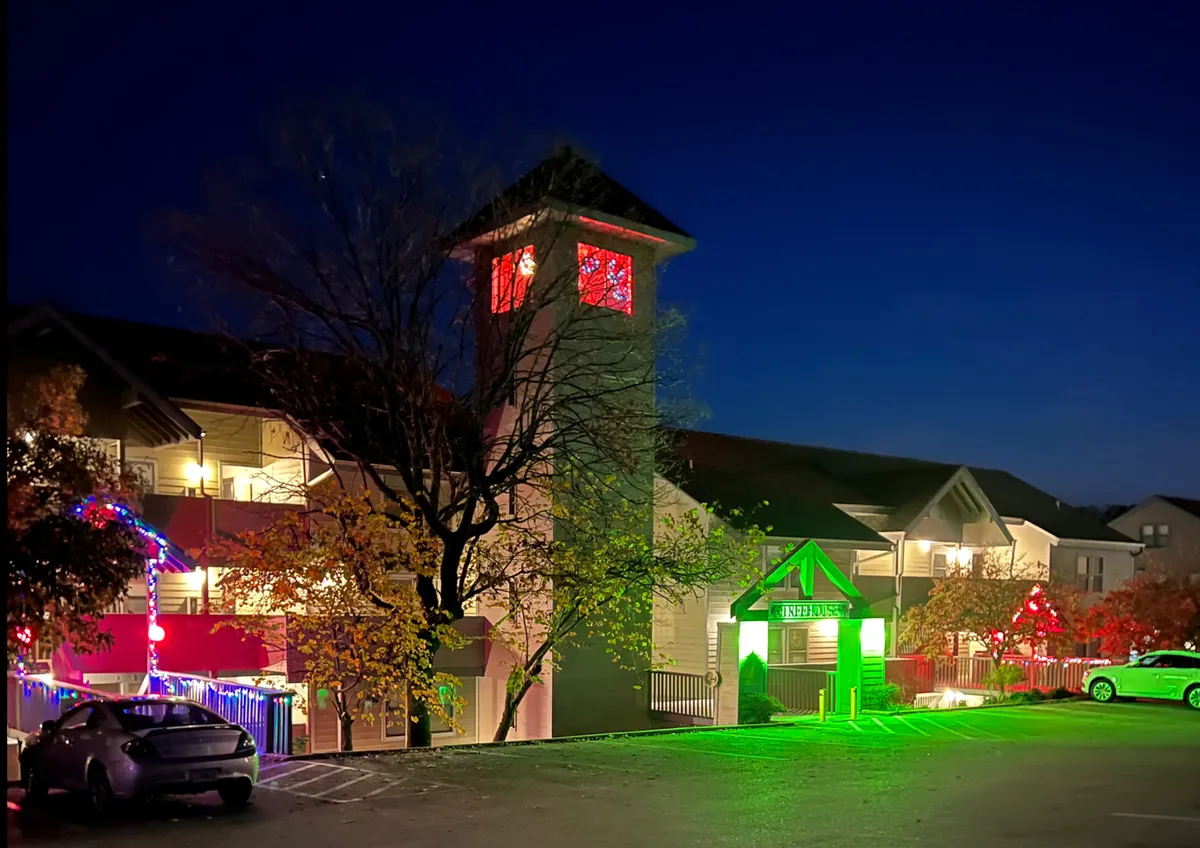 A lively exterior scene featuring a clock tower bathed in colored lights, an illuminated entrance sign, and a festive atmosphere that hints at the area's vibrant nightlife and entertainment options. The evening setting captures the spirit of going out and enjoying local attractions.