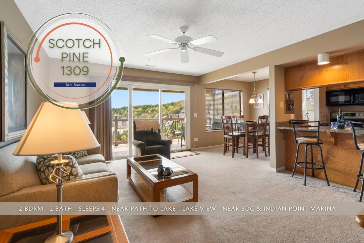 A bright, open-concept living and dining area with large windows showcasing a stunning lake view. Comfortable seating invites relaxation, while a dining table and kitchen bar with stools create spaces for meals and gatherings. Sunlight pours in, illuminating the plush furnishings and the seamless flow between the living, dining, and kitchen zones.