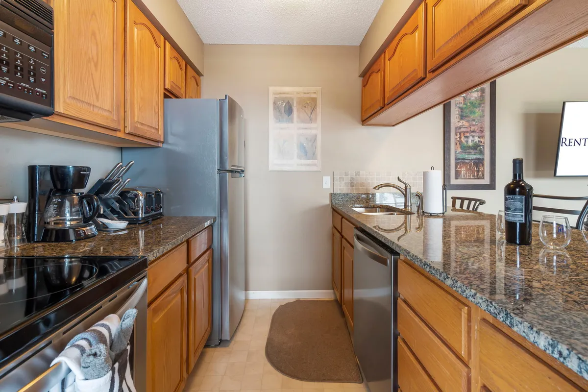 This image features a kitchen with granite countertops, stainless steel appliances, and visible kitchenware, conveying a modern and well-equipped cooking space. The overall mood is cozy, and the countertops and appliances are highlighted as focal points.