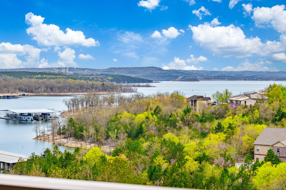 A panoramic view of Table Rock Lake with distant hills, lush greenery, and houses dotting the shoreline. The sky is tinged with sunset colors, enhancing the tranquil mood. The scene invites exploration and connection with nature.