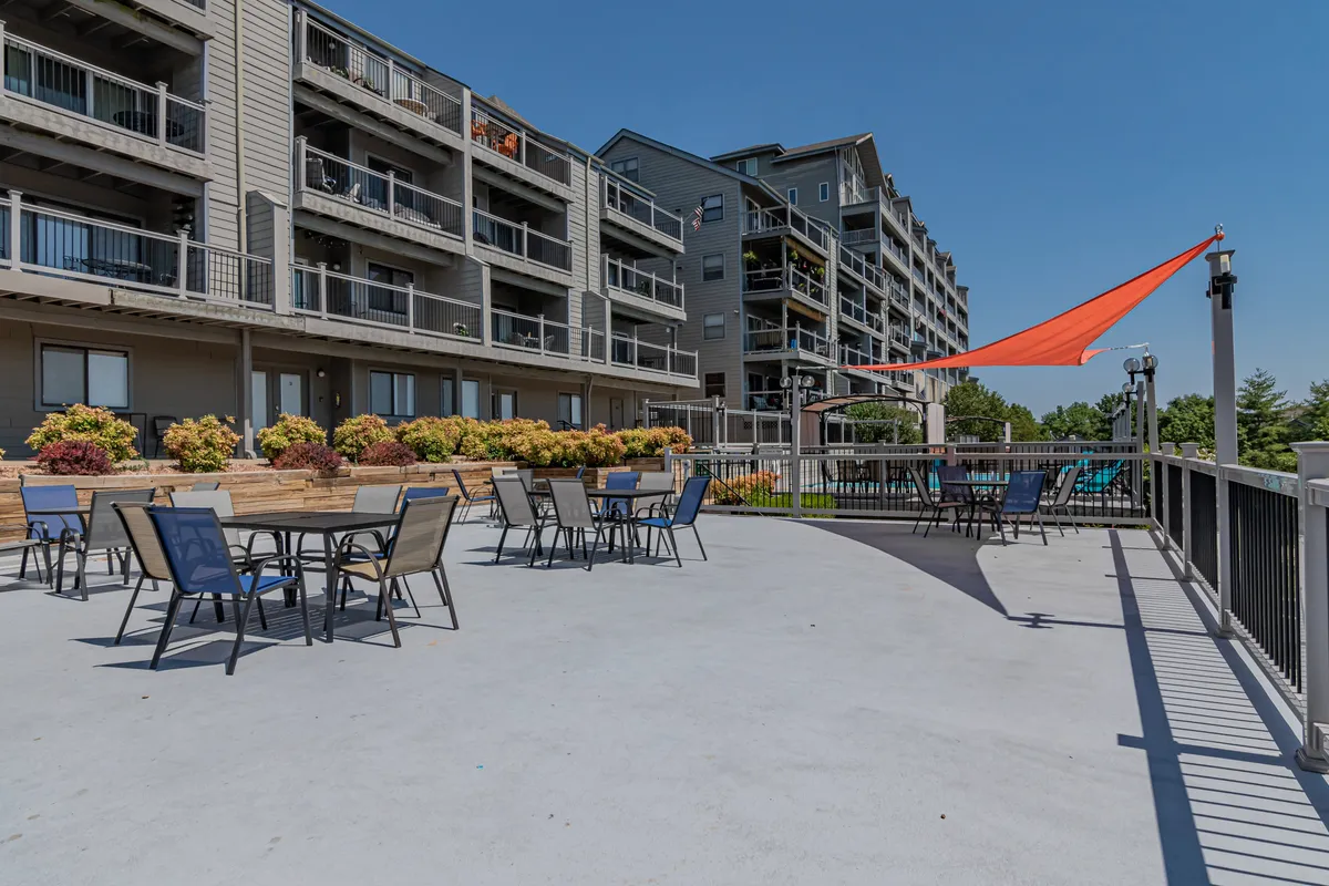 This exterior image highlights a lively outdoor seating area adorned with colorful plants, an orange shade sail, and visible balconies. The communal patio space suggests opportunities for socializing, alfresco dining, or simply relaxing—activities that align with gathering after a day of golf or outdoor pursuits.