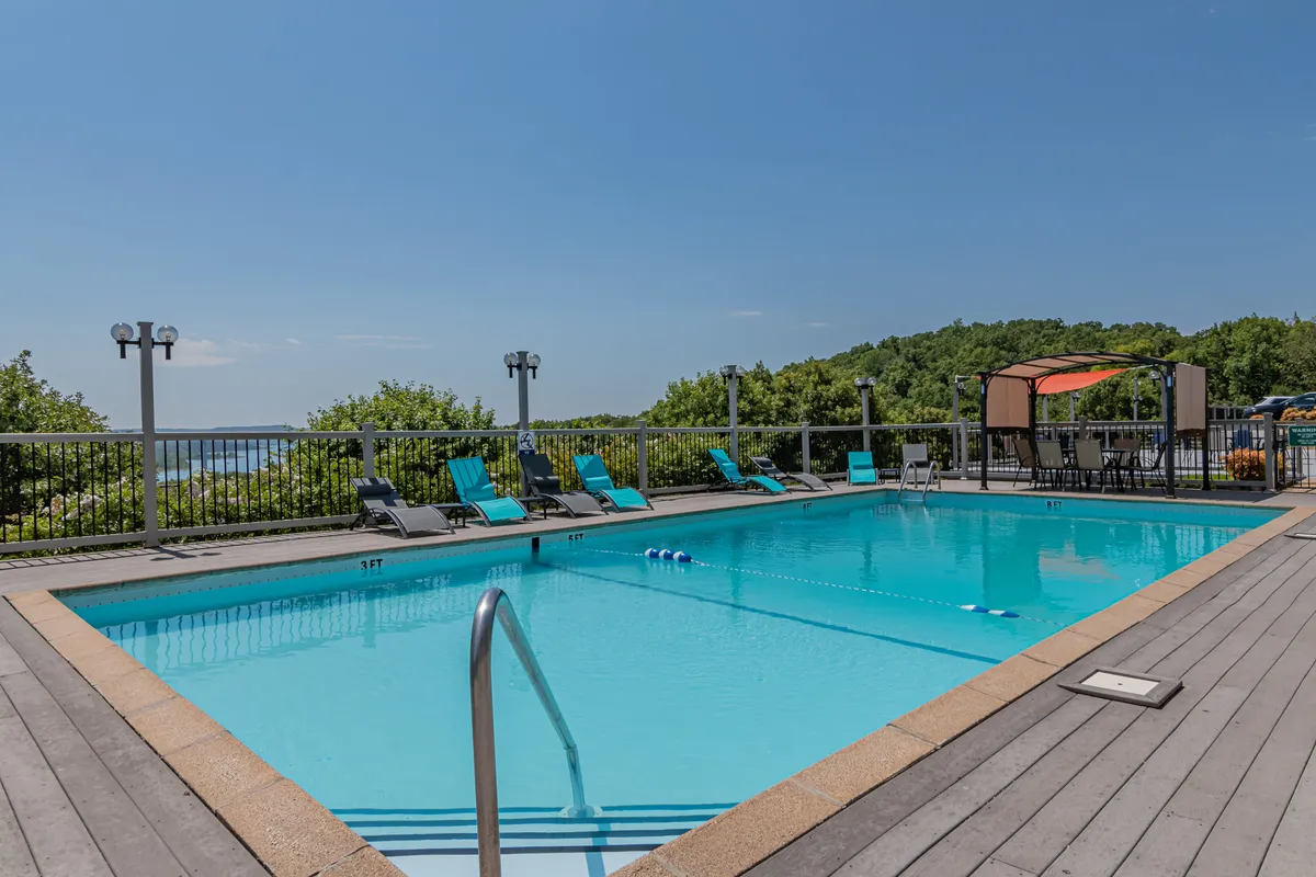 A welcoming outdoor swimming pool surrounded by lounge chairs, a canopy, and lush greenery, set against a soft evening light. The space suggests relaxation and social gatherings, offering a taste of the amenities guests can enjoy upon returning from a night out.